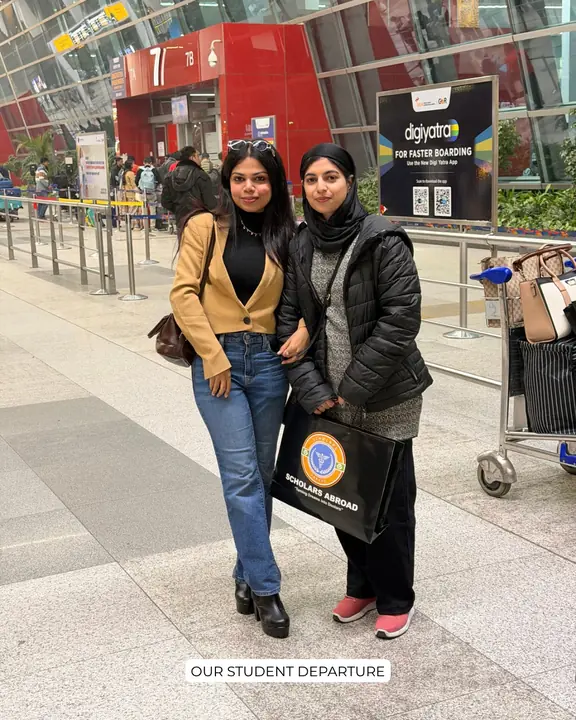 A student in a black jacket with a Scholars Abroad representative and luggage at an airport