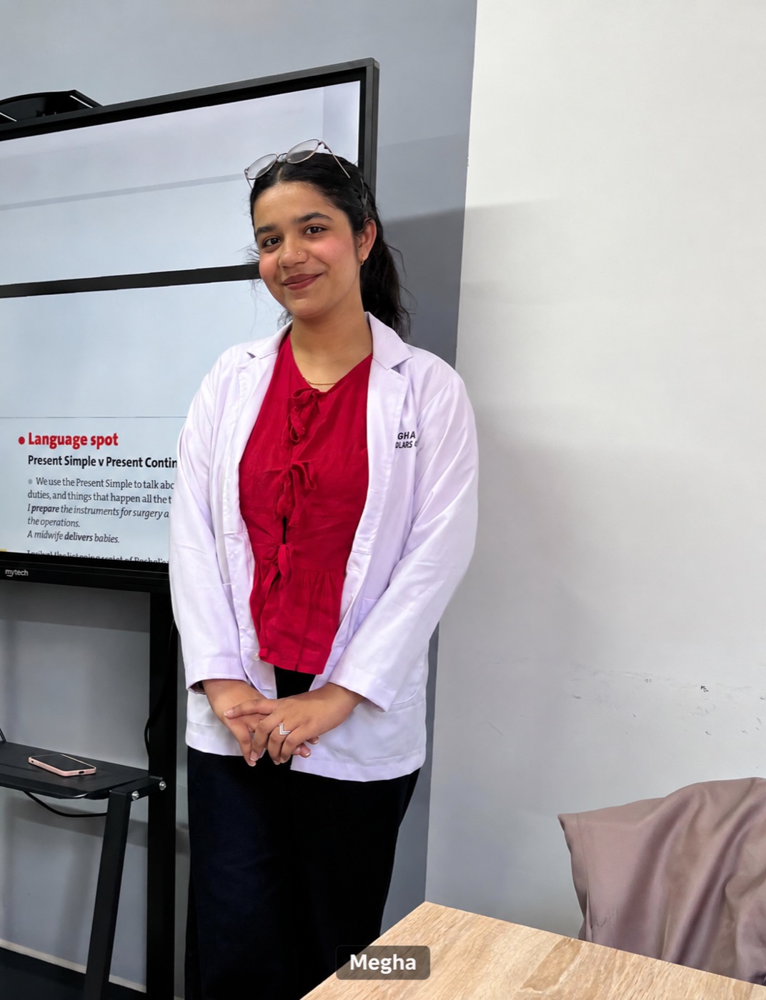 Megha, an Indian medical student, wearing a white coat in her classroom in Uzbekistan.