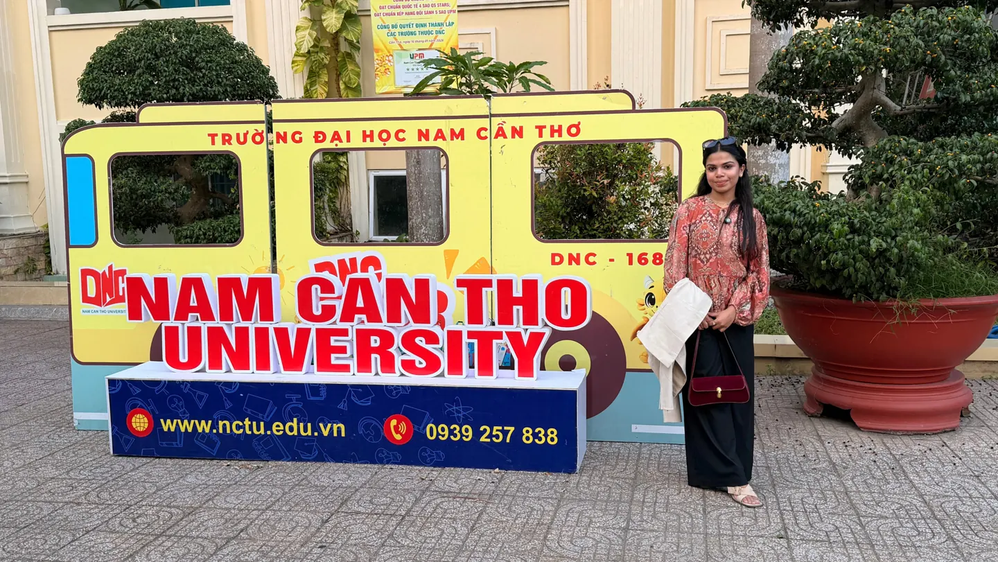 Scholars Abroad representative beside Nam Can Tho University campus signage